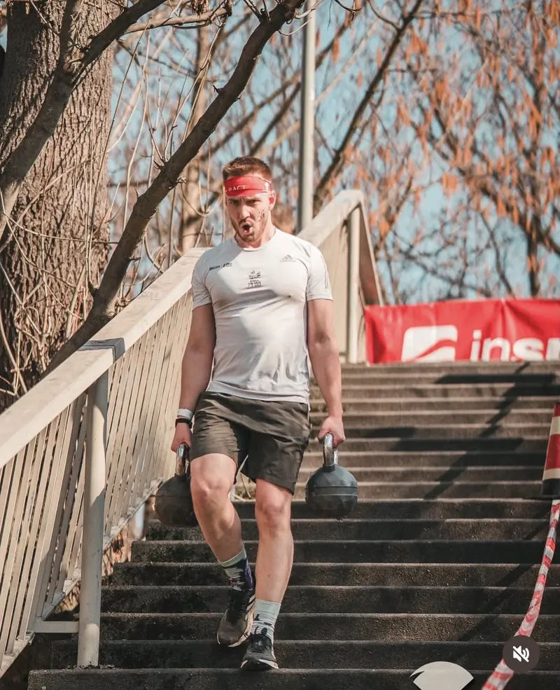 Athlete carrying two kettlebells down a flight of stairs